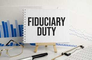 fiduciary duty words on notebook and pen, glasses and charts photo