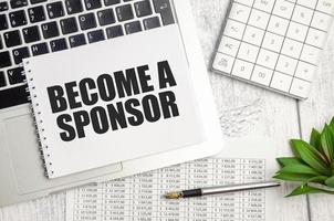 BECOME A SPONSOR text and notepad with pen, charts and calculator photo