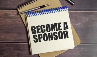 BECOME A SPONSOR text on wooden background photo