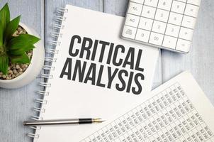 CRITICAL ANALYSIS word on notepad with glasses and chart photo