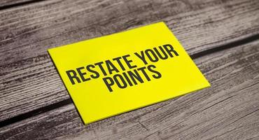 Text sign showing Restate your points on yellow sticker and wooden background photo