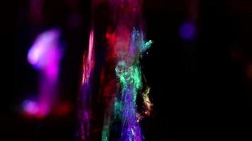 sfondo colorato spruzzi di acqua nel scuro. flusso di acqua è illuminato di ghiaccio led. gocce di liquido di diverso colori. struttura di Fontana fluire. dettagli di urbano infrastruttura. video