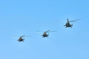 Three military helicopters flying in blue sky performing demonstration flight, air show, copy space photo