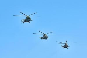 Three military helicopters flying in blue sky performing demonstration flight, air show, copy space photo