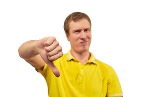 Unhappy annoyed man in yellow T-shirt showing thumbs down gesture isolated on white background photo