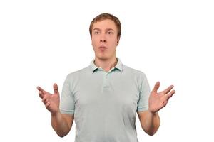 Confused young guy shrugged shoulders, guy in casual T-shirt spread arms isolated white background photo