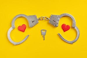 Handcuffs smile shape on yellow background. Freedom concept. photo