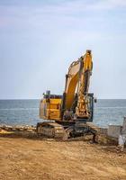 excavadora sobre orugas después de las obras en el sitio de construcción en la playa del mar foto