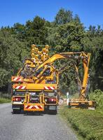 tractor con cortacésped mecánico cortando hierba al lado de la carretera asfaltada. los servicios viales se dedican al paisajismo alrededor de las carreteras. vista vertical foto