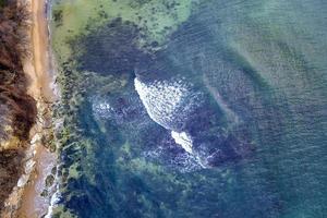 vista aérea de drones de la superficie de la costa con olas y piedras. vista superior foto