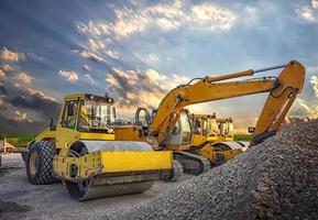 Parked drum roller and excavators at the construction site, after work photo