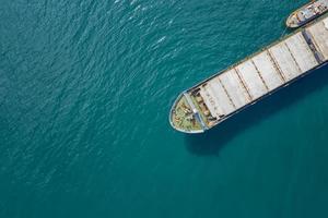 Aerial shot of a cargo ship approaching port with help of towing ship photo