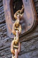 View of rusty anchor chain coming out of a wooden sailing ship. Vertical view photo