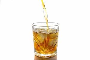 Pouring whiskey in a glass with ice. front view. Isolated photo