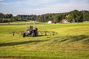 The tractor and hay tedder prepare hay harvest for cultivation. Agriculture and agronomy concept. Selective focus photo