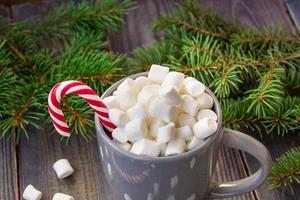 Hot coffee chocolate with marshmallow on rustic wooden table background, candy canes gift boxes fir tree photo