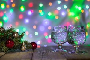 dos copas de champán de navidad con un árbol de navidad decorado con bolas rojas y plateadas contra un fondo claro de bokek foto