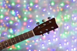 el cuello de la guitarra acústica en el fondo bokeh de luz navideña foto