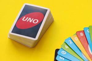 Ternopil, Ukraine - May 8, 2022 Many colorful UNO game cards on yellow background. UNO is an American shedding-type card game that is played with a specially printed deck photo