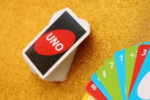 Ternopil, Ukraine - May 8, 2022 Many colorful UNO game cards on golden background. UNO is an American shedding-type card game that is played with a specially printed deck photo