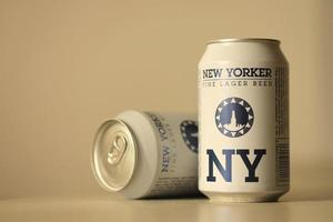TERNOPIL, UKRAINE - JULY 18, 2022 Two cans of New Yorker fine lager beer with original logo and design on brown retro background photo