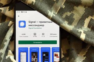 Ternopil, Ukraine - May 8, 2022 Signal Private Messenger app play store page on the display of a black mobile smartphone on ukrainian military camouflage photo