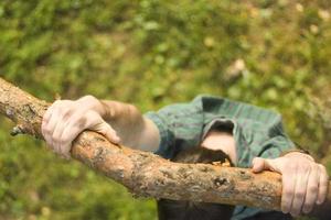Hands hold on to branch. Guy is hanging on tree branch. Man on top. Strong grip with hands. photo