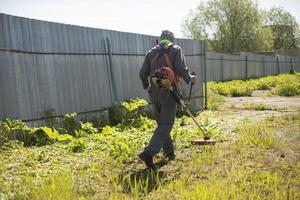 el trabajador corta el césped. jardinero con cortadora de césped a gasolina. foto