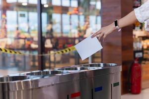 Woman putting paper into trash bin in shopping mall. photo