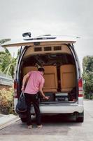 Road trip driver loading luggage on traveling van. photo