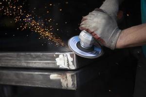 Metal processing. Grinder in hand. Worker holds tool. Creation of steel structure. photo