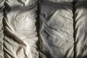 Matting sheet on bed. Texture of fabric in sunlight. photo