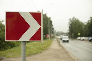 Sign sharp turn. Red road sign. Arrow pointer on road. photo