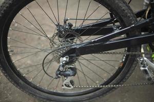 Black bike wheel. Bike details on street. Spokes and tire. photo