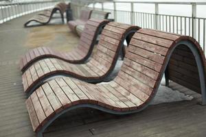 Benches for recreation in park. Comfortable seating. Sun beds on waterfront. photo
