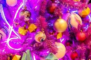 close up of christmas trees decoration with toys and garlands. Festive greeting card for winter holidays. Neon trendy colors photo