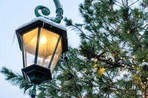Close up of retro street lantern and fur tree with garland. Christmas mood in the city photo