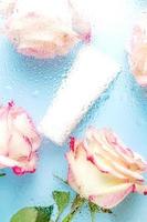 cosmetic white tube for face cream, cleanser or body lotion on a blue background with water droplets and the reflection of rose flowers through the glass. The concept of moisturizing cosmetic product photo