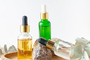 frascos cuentagotas de vidrio con aceite cosmético, aceite esencial o suero en un soporte de piedra con rama de eucalipto productos homeopáticos a base de hierbas cosméticos de spa orgánicos naturales foto