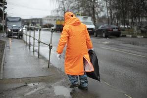 Workers on road. Road workers clean up garbage. People in orange clothes. photo