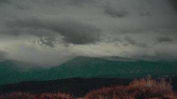las nubes de tormenta de lapso de tiempo viajan sobre una ladera y montañas. video