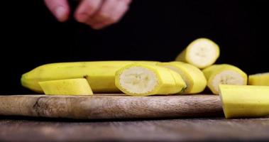 pick up a cut piece of ripe yellow banana from the board photo
