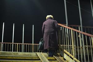 Old woman climbs stairs. Awkward pedestrian crossing. photo