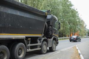 Black truck on road. Freight transport on highway. Car with body. Great trailer. photo