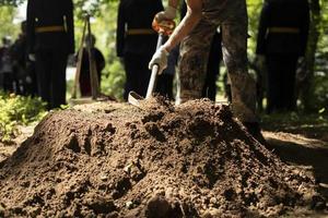 Man digs grave. Worker with shovel. Mounding. photo