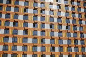 Orange building in modern style. House with identical windows. Lot of apartment building in city. New housing. photo