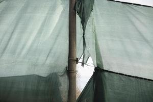 Torn grid in stadium. Green grid around site. Torn fabric. photo