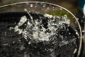 Rain is dripping into bucket. Water splashes in bucket. photo