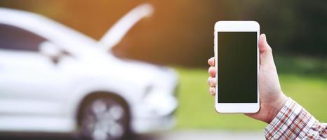 close up businessman hand using a mobile smart phone call a car mechanic ask for help assistance because car broken roadside. people journey friends standing wait beside broken car background. photo