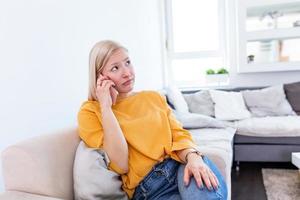 Portrait of unhappy young woman making annoyed phone call at home. dissatisfied girl calling customer service, having problem of conflict during telephone conversation peaking by cell photo